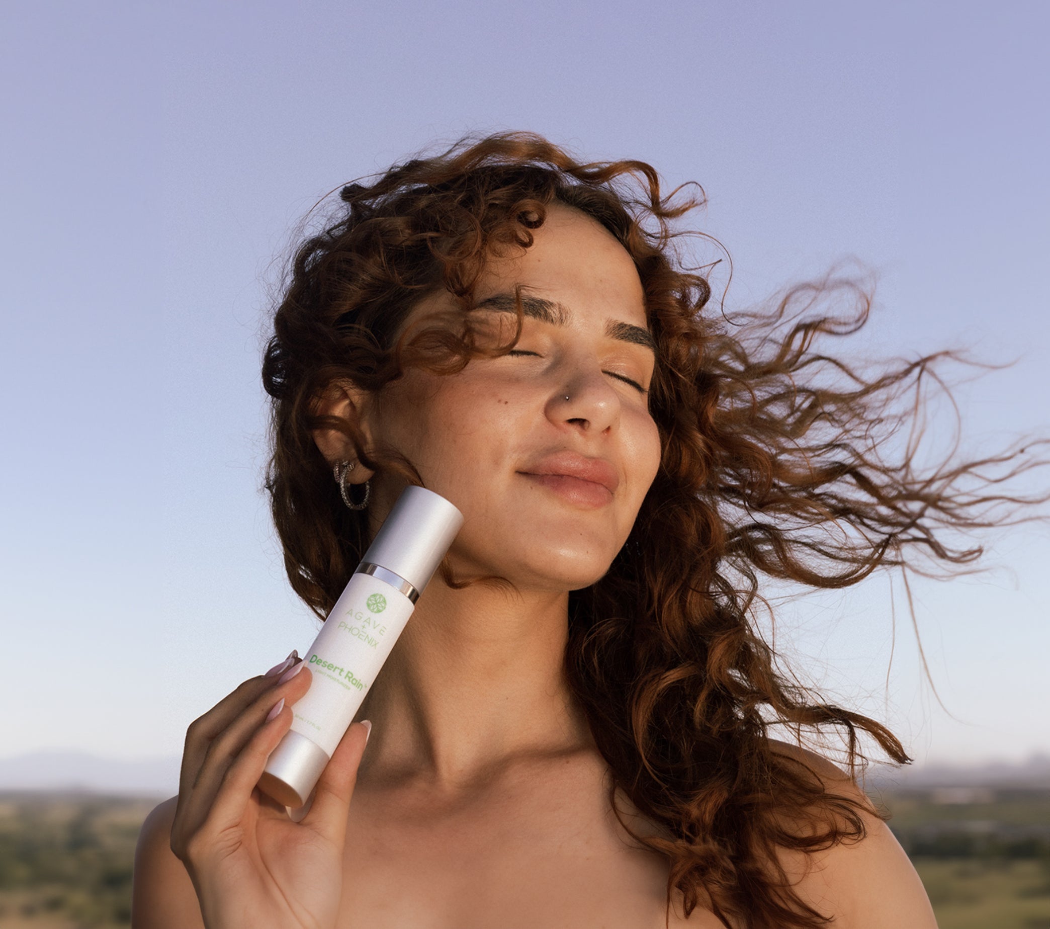 Model holding Desert Rain lightweight moisturizer — hydrating and antioxidant-rich skincare for radiant skin.